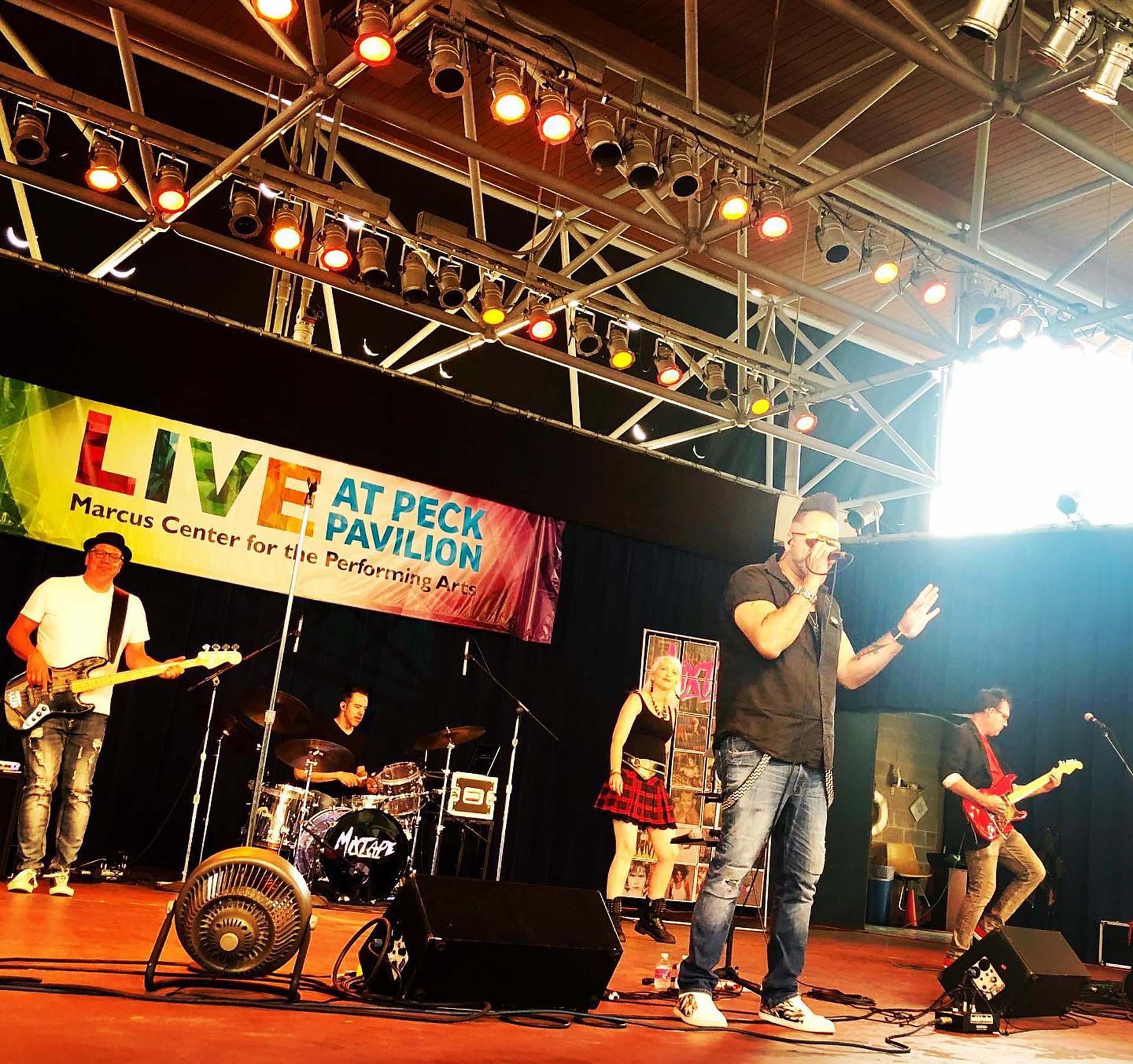 band playing on an outside stage for the Live at Peck Pavilion concert